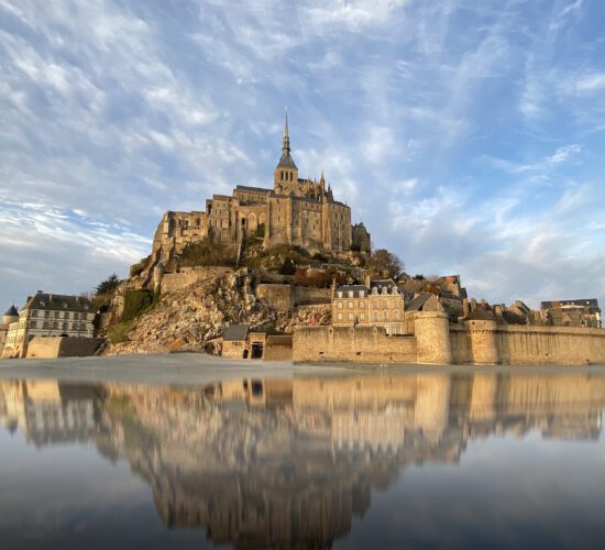 Beautiful Mont Saint Michel with water reflection and clouds on blue sky, France